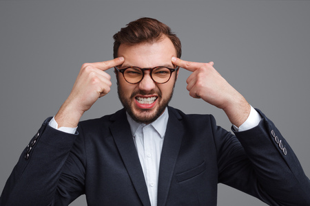 Angry businessman squeezing head with fingersの写真素材