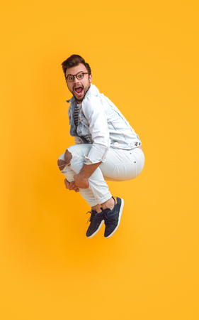 Excited bright man jumping upの写真素材