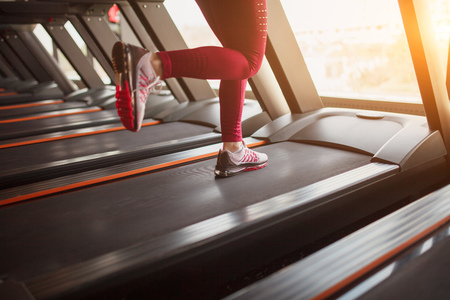Crop sportswoman running on treadmill