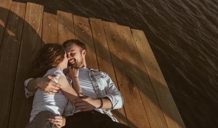 Cuddling young couple lying on pierの写真素材