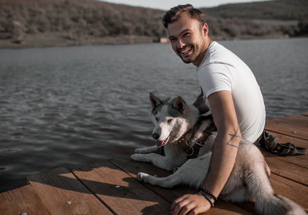 Happy man with dog on pierの写真素材