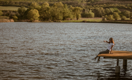 Woman on pier pointing away in natureの写真素材