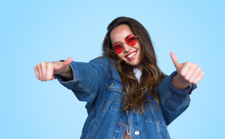Bright teenage girl showing thumbs upの写真素材