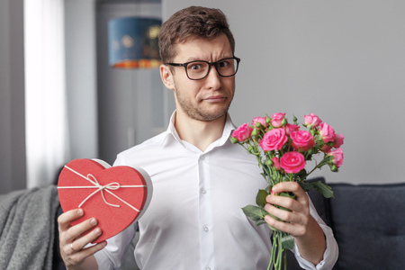 Displeased male with Valentines Day present and flowersの写真素材