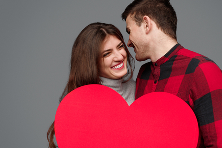 Laughing couple holding huge heartの写真素材