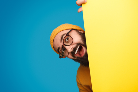 Cheerful man peeking out from behind posterの写真素材