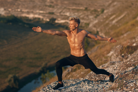 Muscular man doing yoga in natureの写真素材