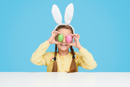 Funny girl with Easter eggs near eyes