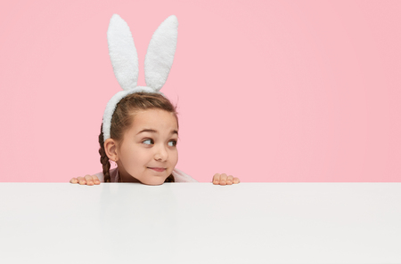 Playful little girl in white bunny earsの写真素材