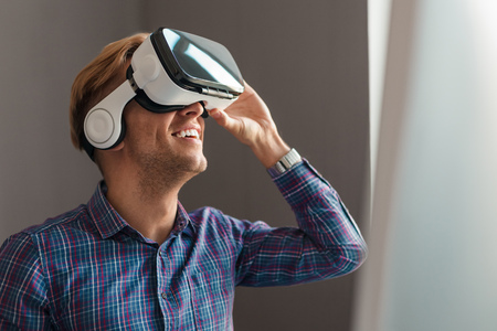 Smiling guy in VR glasses looking up
