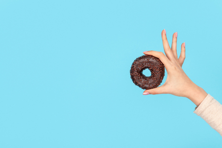 Hand holding delicious chocolate doughnutの写真素材