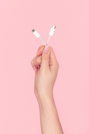 Crop female hand with white cable adapter