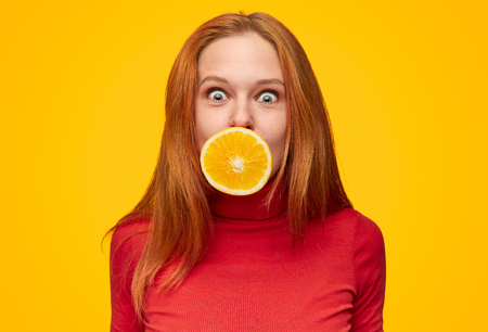 Ginger model with orange in mouthの写真素材