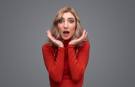 Shocked lady in sweater looking at cameraの写真素材