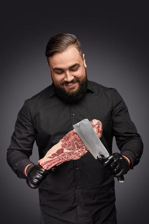 Smiling butcher scratching meat with knifeの写真素材