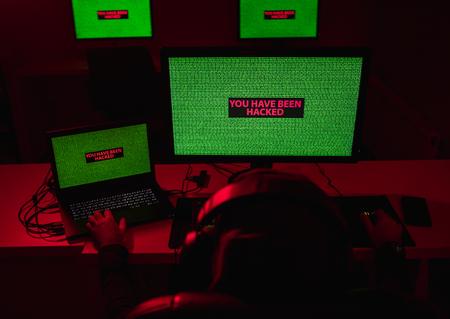 Anonymous male looking at screens with hacking alertの写真素材