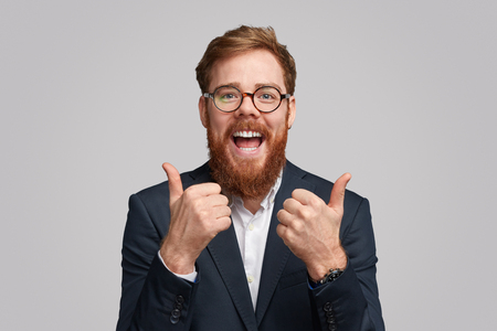 Thrilled cool businessman showing thumbs upの写真素材