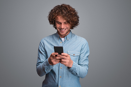 Smiling guy using smartphoneの写真素材