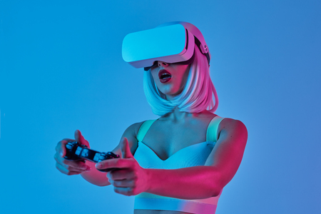 Amazed woman playing VR games with controllerの写真素材