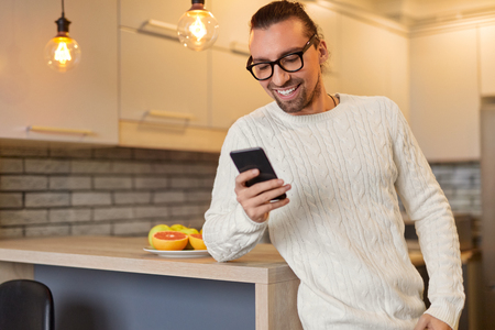 Stylish male using smartphone in kitchenの写真素材