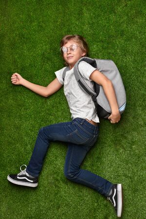 Schoolboy running over green lawn