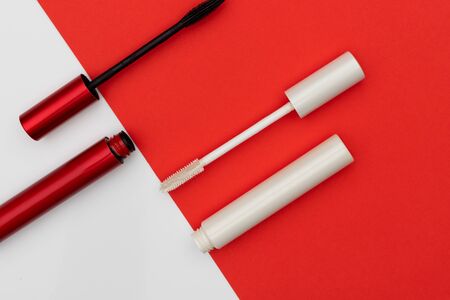 From above tubes and brushes of black and white mascara placed near diagonal line of two colored backgroundの写真素材