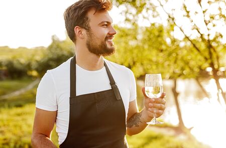 Smiling man with glass of wine in countrysideの写真素材