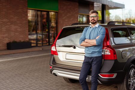 Confident man leaning on car
