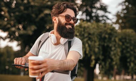 Smiling hipster with hot drink riding electric vehicle in parkの写真素材