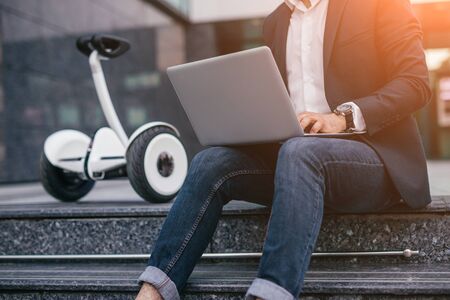 Crop businessman using laptop near gyroscooterの写真素材