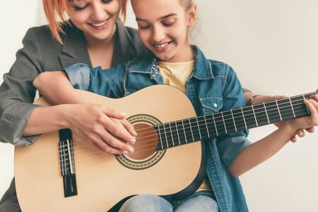 Smiling woman teaching girl to play guitarの写真素材