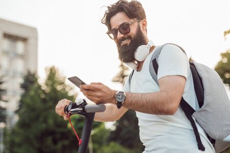 Smiling hipster using modern gadgets in everyday lifeの写真素材