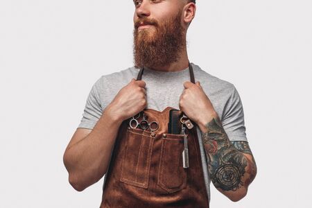Stylish barber in apron looking awayの写真素材