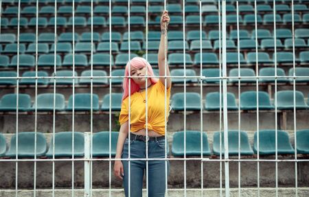 Stylish teenager behind fence on stadiumの写真素材