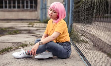 Modern teenager sitting near fenceの写真素材