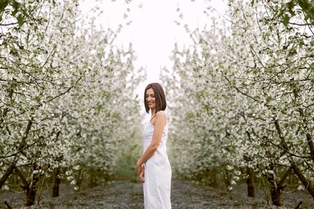 Peaceful stylish woman standing beside blossoming spring treesの写真素材