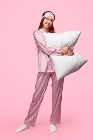 Cheerful young lady embracing pillowの写真素材