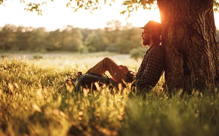 Bearded traveler resting near treeの写真素材