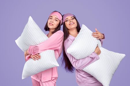 Smiling friends with pillows during pajama partyの写真素材
