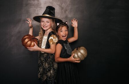 Frightening girls in Halloween outfits with pumpkins