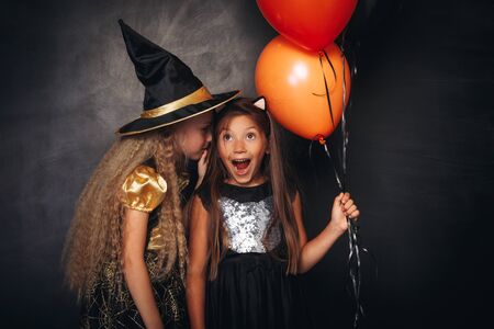 Funny children in Halloween costumes sharing secretの写真素材