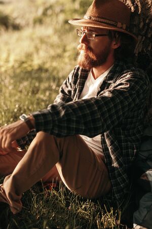 Bearded hiker sitting under tree in natureの写真素材