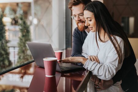 Happy couple using laptop in restaurant togetherの写真素材