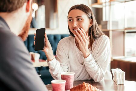 Cheerful woman showing social media to boyfriendの写真素材