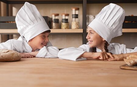 Cheerful little bakers looking at each other