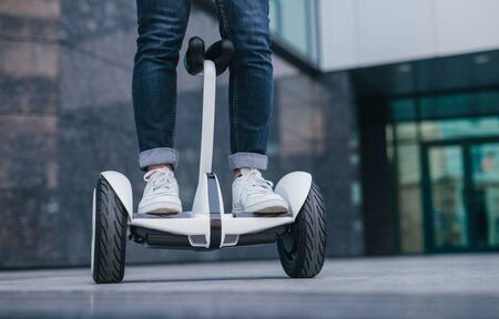 Crop hipster riding electric vehicle on street