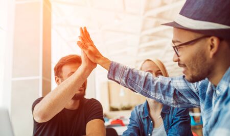 Multiethnic friends giving high five in cafe