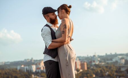 Stylish couple kissing against city