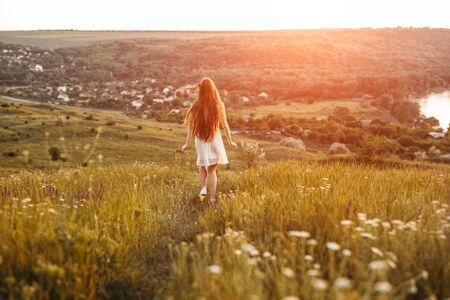Unrecognizable young female running in field in eveningの写真素材