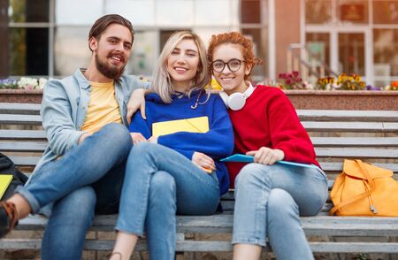 Happy students hugging on bench togetherの写真素材